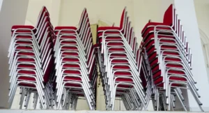 Chaises empilables pour événement rangées en colonne dans une salle de collectivité