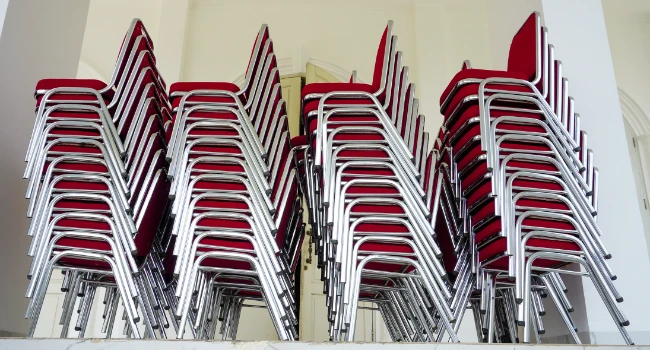 Chaises empilables pour événement rangées en colonne dans une salle de collectivité